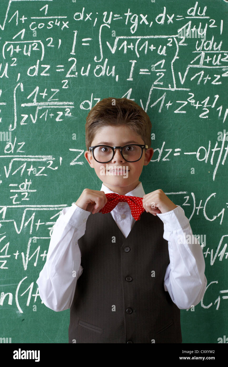 Scolaro con gli occhiali e un filtro bow tie di fronte a una lavagna con le equazioni matematiche Foto Stock