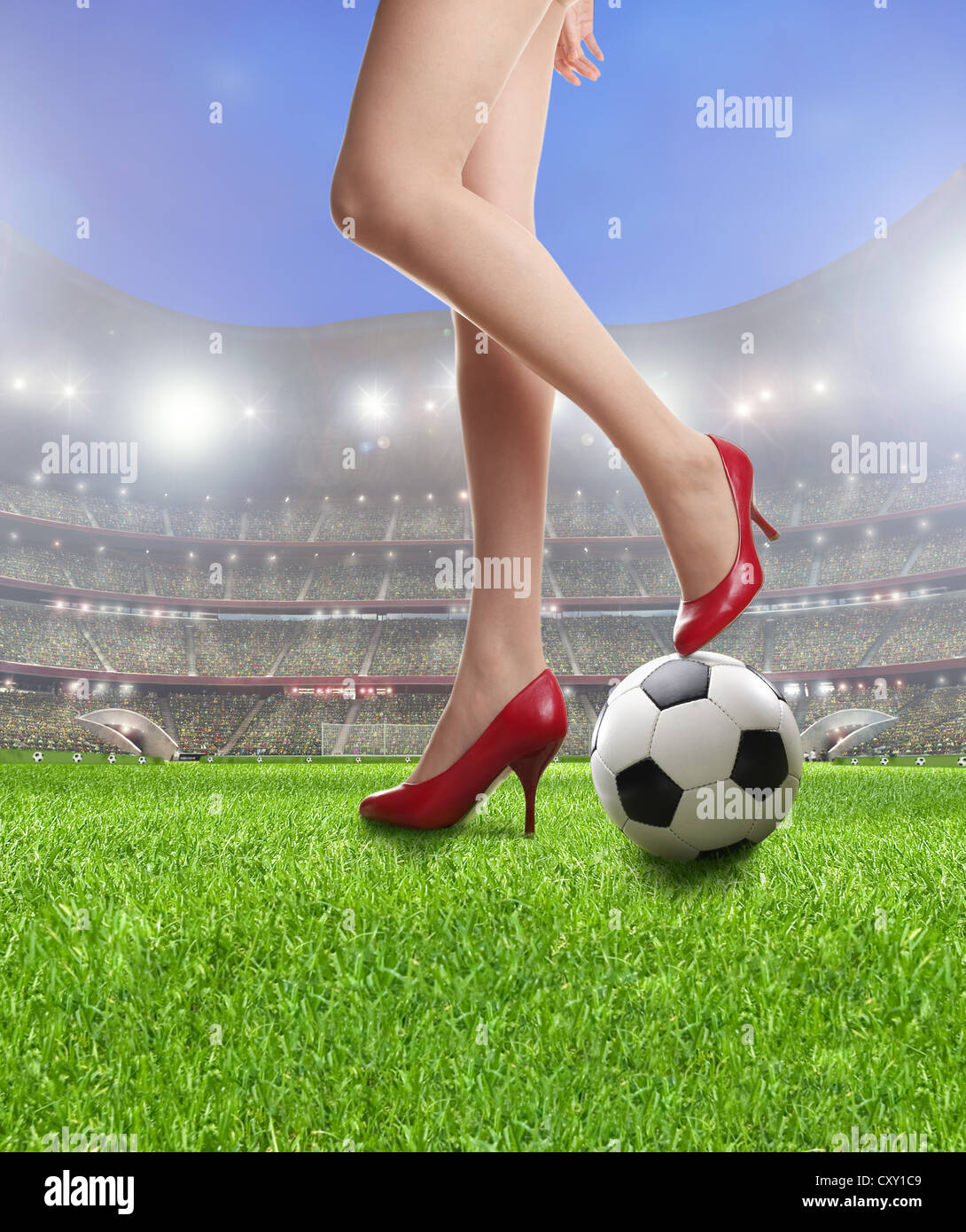 La donna per le gambe di indossare tacchi alti, sexy, con un pallone da calcio in uno stadio di calcio Foto Stock