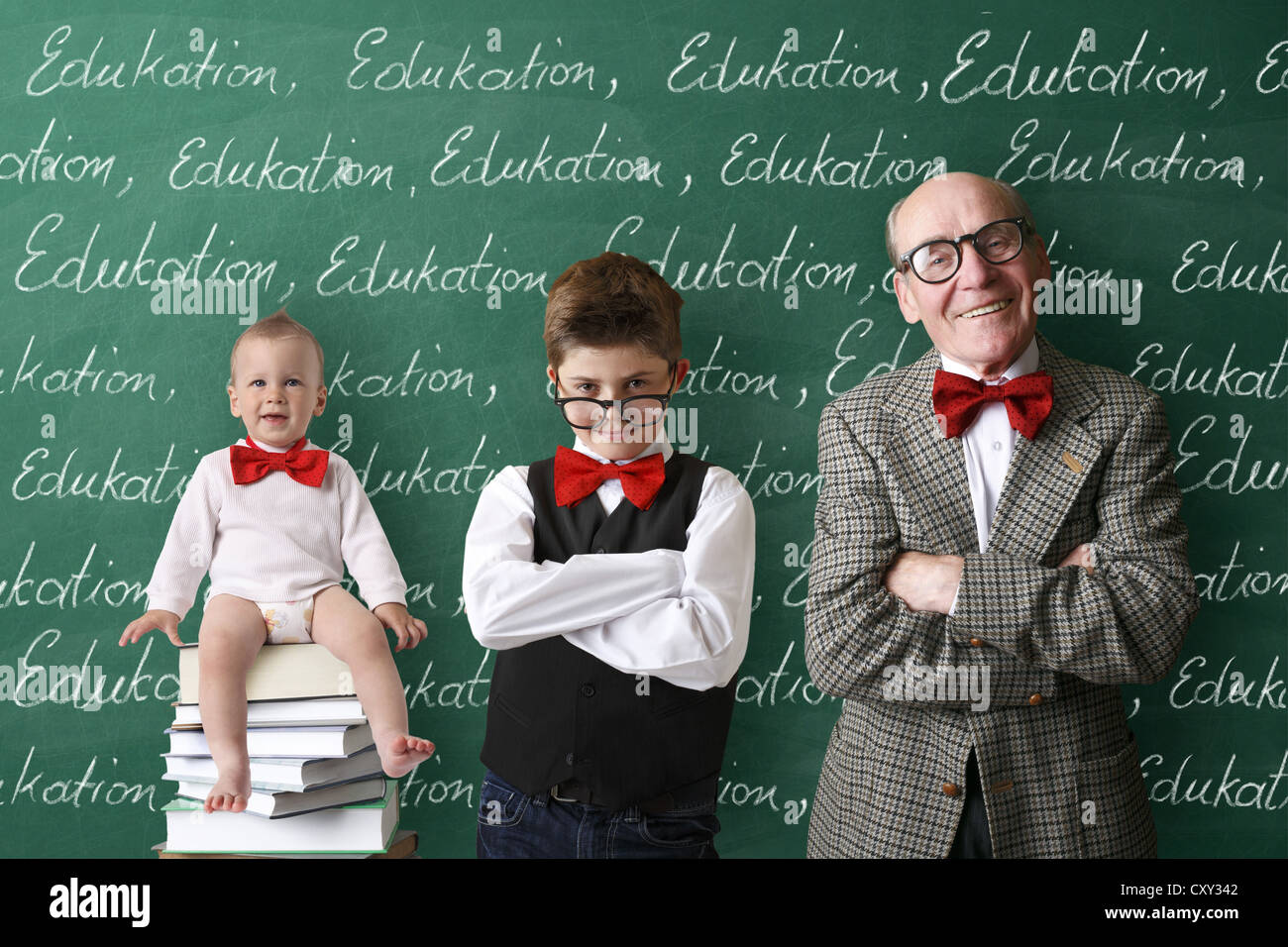 Infantile, scolaro e un professore in piedi di fronte alla scuola lavagna con la parola istruzione scritto ripetutamente Foto Stock