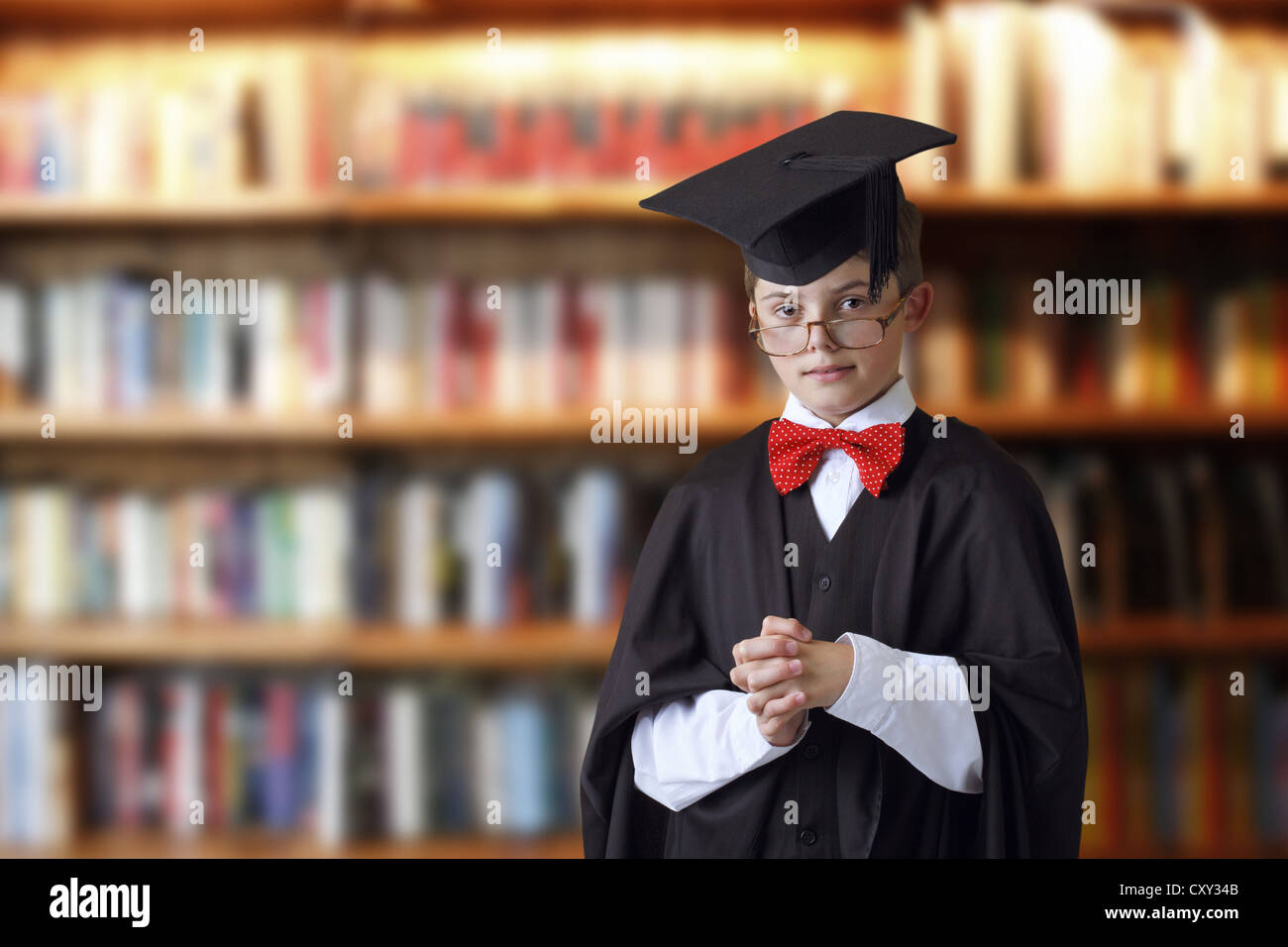 Scolaro indossando un cappello di laurea in una libreria Foto Stock