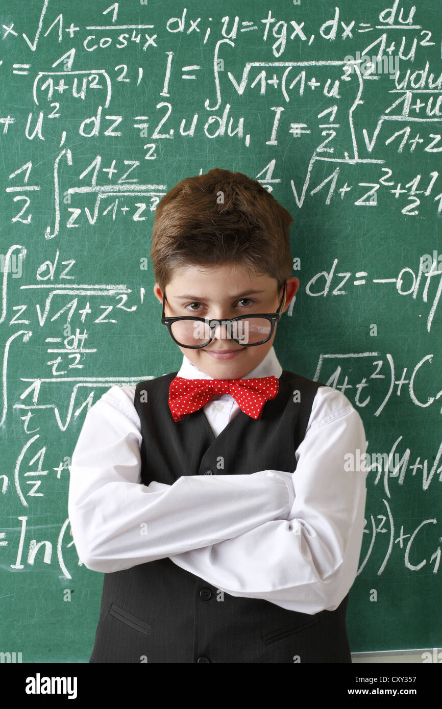 Scolaro con gli occhiali e un filtro bow tie di fronte a una lavagna con le equazioni matematiche Foto Stock