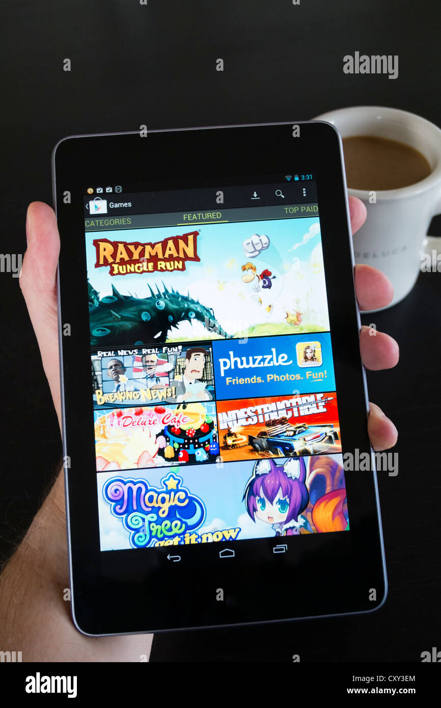Uomo con Google Nexus 7 computer tablet android in esecuzione mostra giochi in vendita presso Google Play store Foto Stock