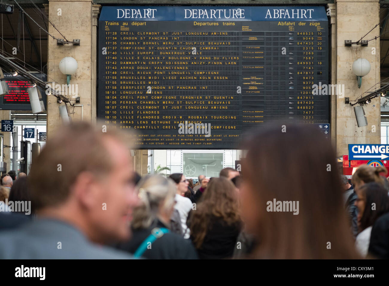 Dettaglio delle destinazioni sulla scheda di partenze e molti passeggeri in attesa per i treni alla stazione ferroviaria Gare du Nord di Parigi Franc Foto Stock