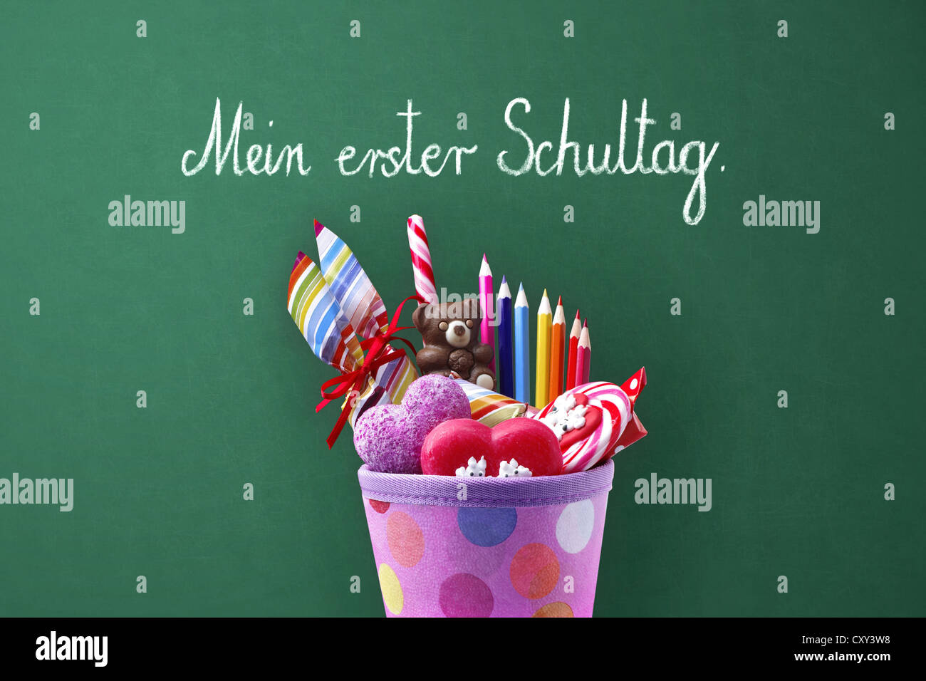 Schultuete o a scuola a forma di cono con doni e dolciumi di fronte a una lavagna di scuola con il messaggio Mein erster Schultag, Tedesco Foto Stock
