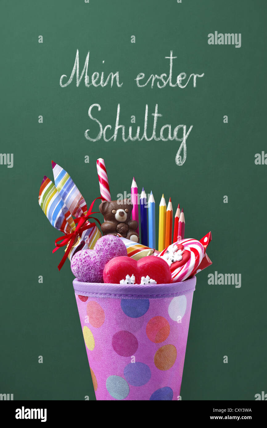 Schultuete o scuola cono riempito con doni e dolciumi di fronte a una lavagna di scuola con la voce Mein erster Schultag, Foto Stock