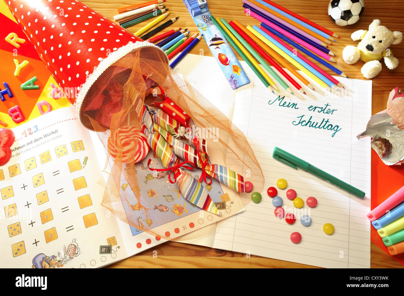 Schultuete o scuola cono riempito con doni e dolciumi accanto a matite colorate e un notebook con la voce Mein erster Foto Stock