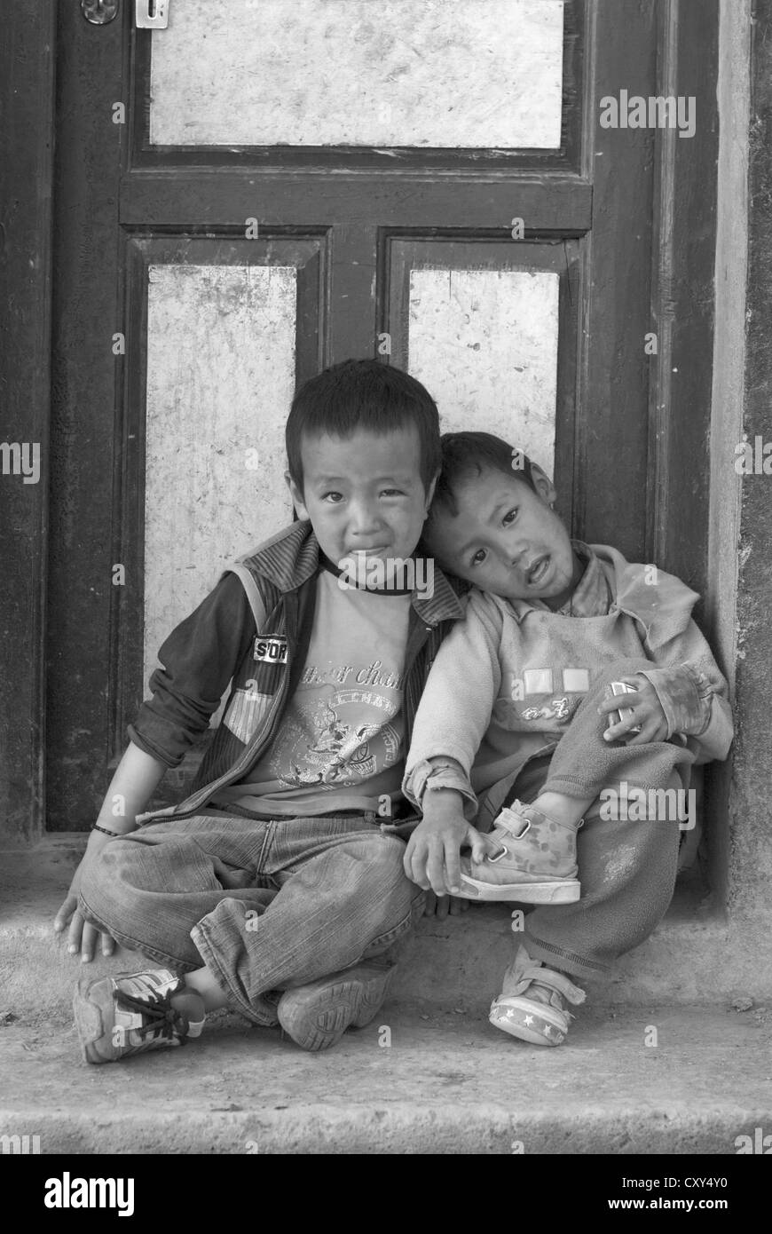 Due amici che siedono alla porta di una casa nel villaggio di fango, Spiti, India settentrionale Foto Stock