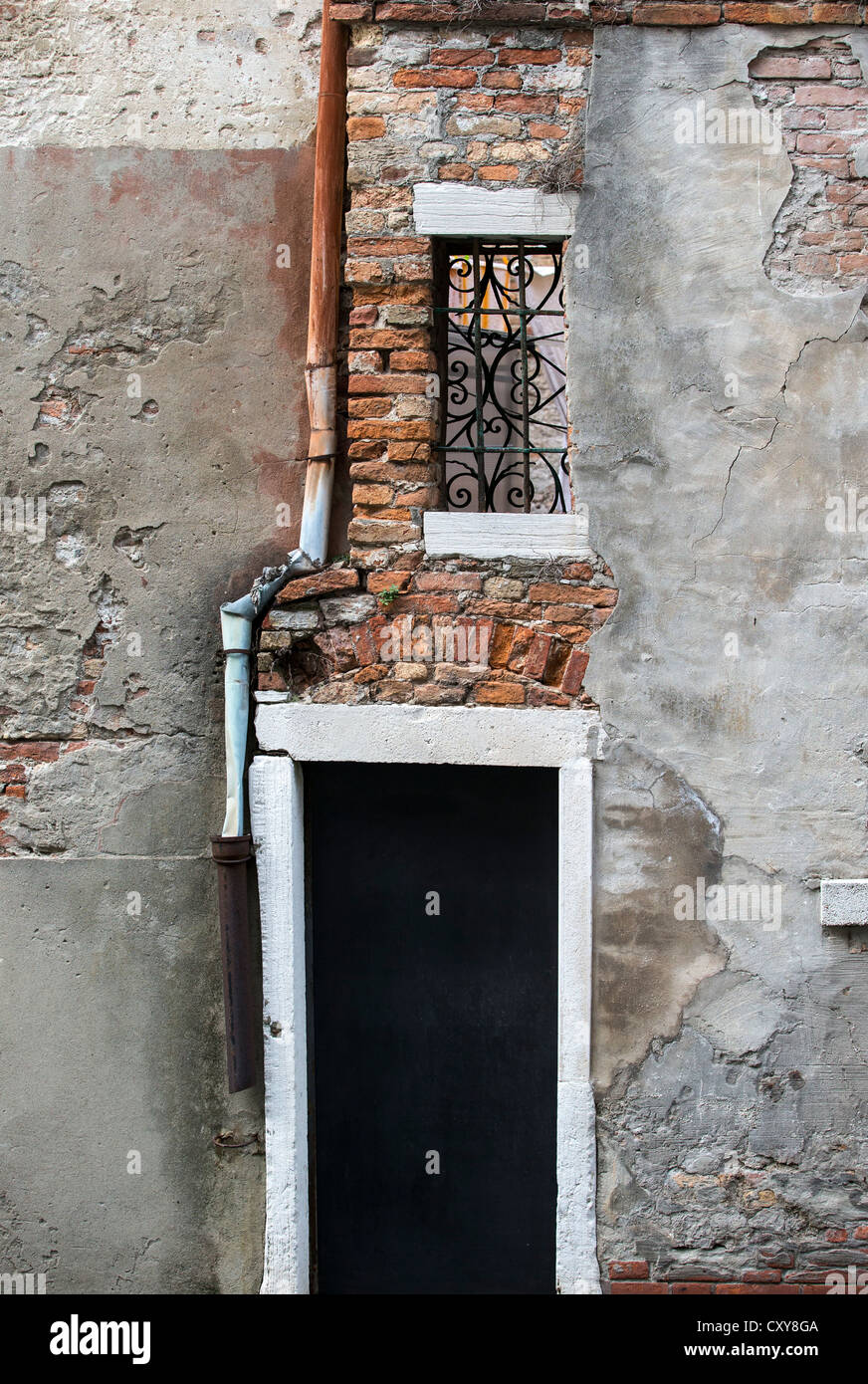 Piuttosto fatiscente porta con danneggiato e rusty drainpipe e finestra con battuto irol-grill. Foto Stock