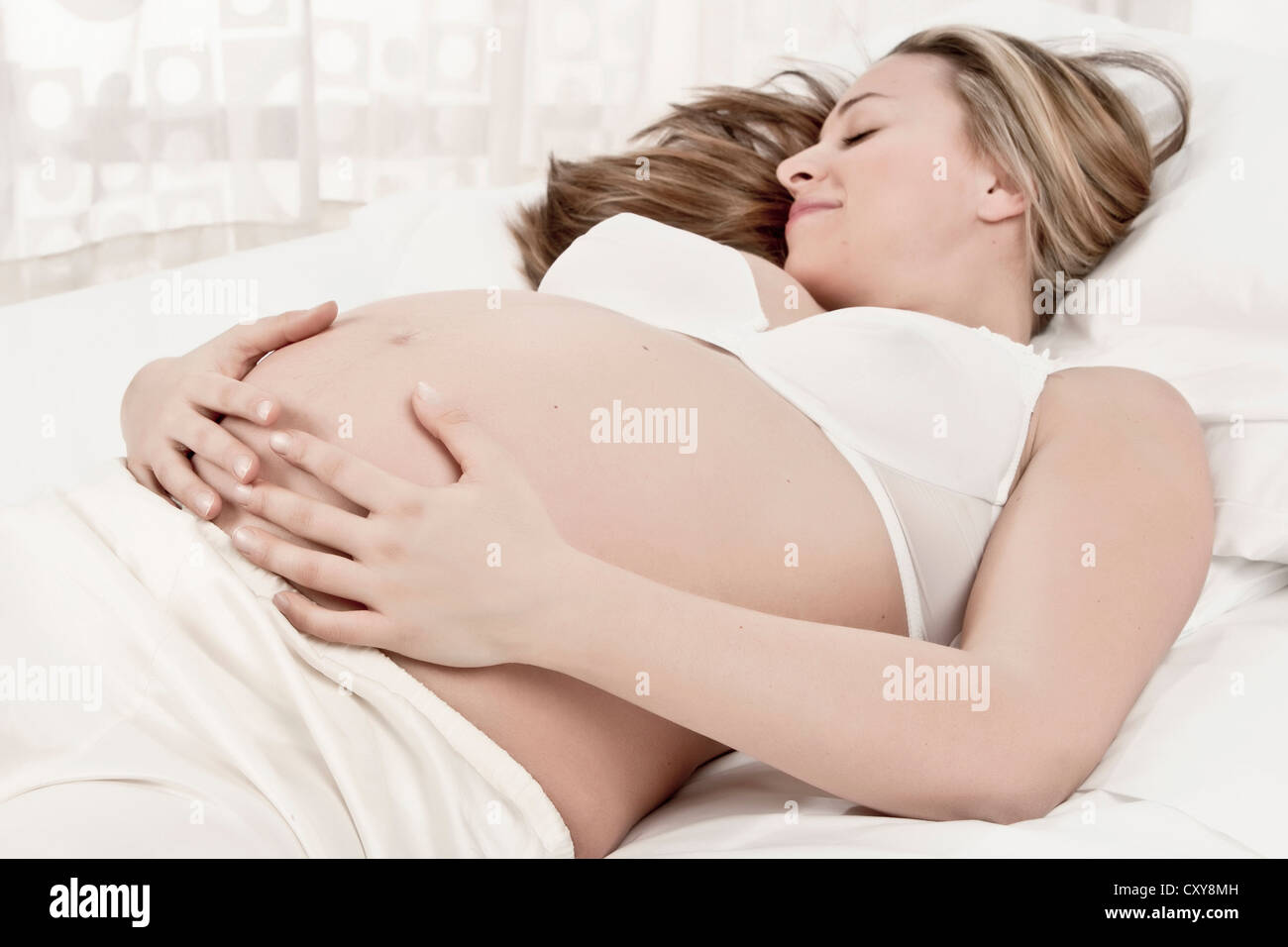 Donna incinta posa a letto Foto Stock