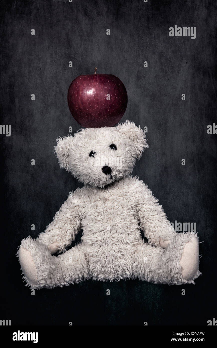 Un orsacchiotto bianco con una mela rossa sulla testa Foto Stock