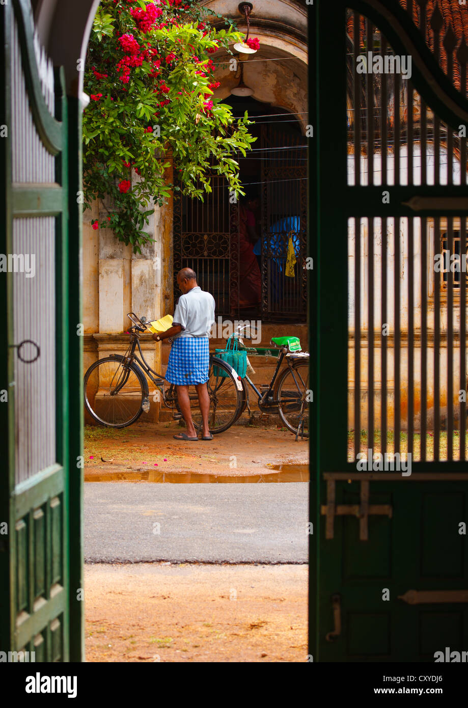 L uomo e la sua bicicletta visto da un passato antico ingresso di casa in Kanadukathan Chettinad, India Foto Stock