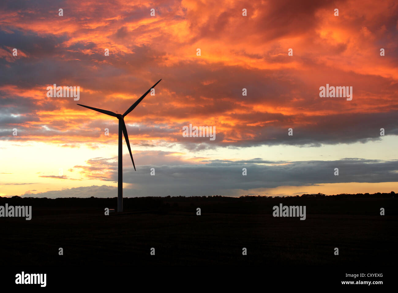 Turbina eolica con un rosso/arancione tramonto, UK. Foto Stock