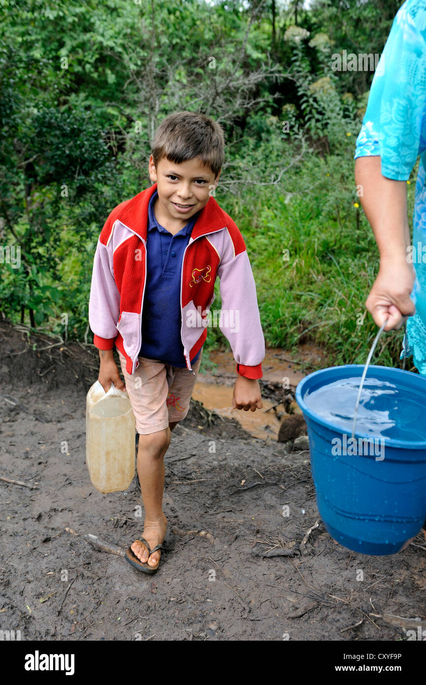 Madre e figlio di recupero di acqua da un flusso, Comunidad Martillo, Caaguazu, Paraguay, Sud America Foto Stock