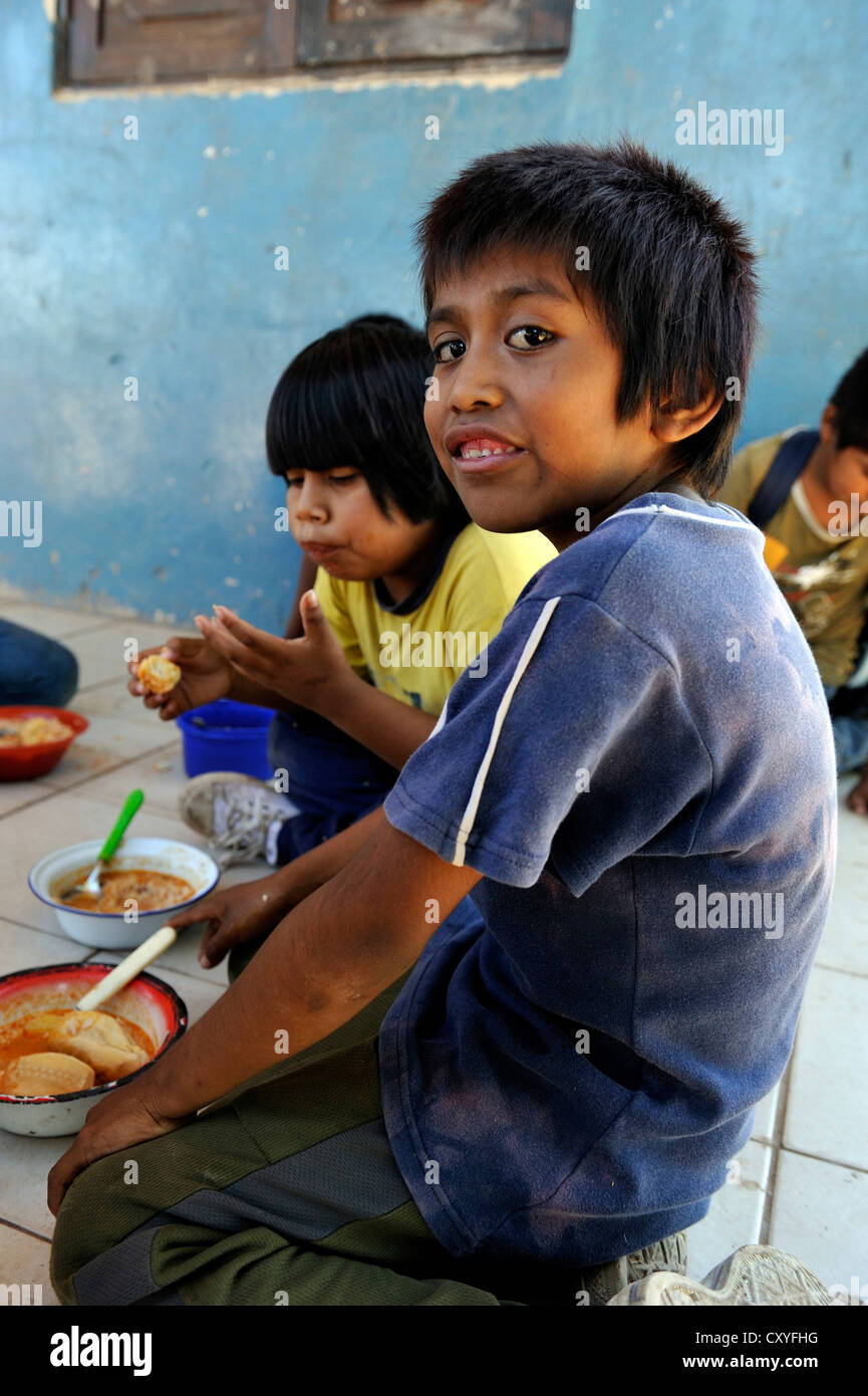 I ragazzi di mangiare il pranzo che era previsto presso la scuola del paese, villaggio degli indigeni Wichi persone, Comunidad Tres Pocos Foto Stock