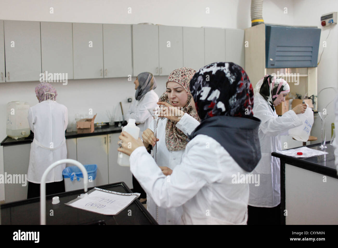 Studentesse palestinesi vestite di cappotti di laboratorio che lavorano all'esperimento in un laboratorio di educazione chimica all'università al Quds di Abu Dis o Abu Deis, una comunità palestinese che appartiene al governatorato palestinese di Gerusalemme a sud-est di Gerusalemme in Israele Foto Stock