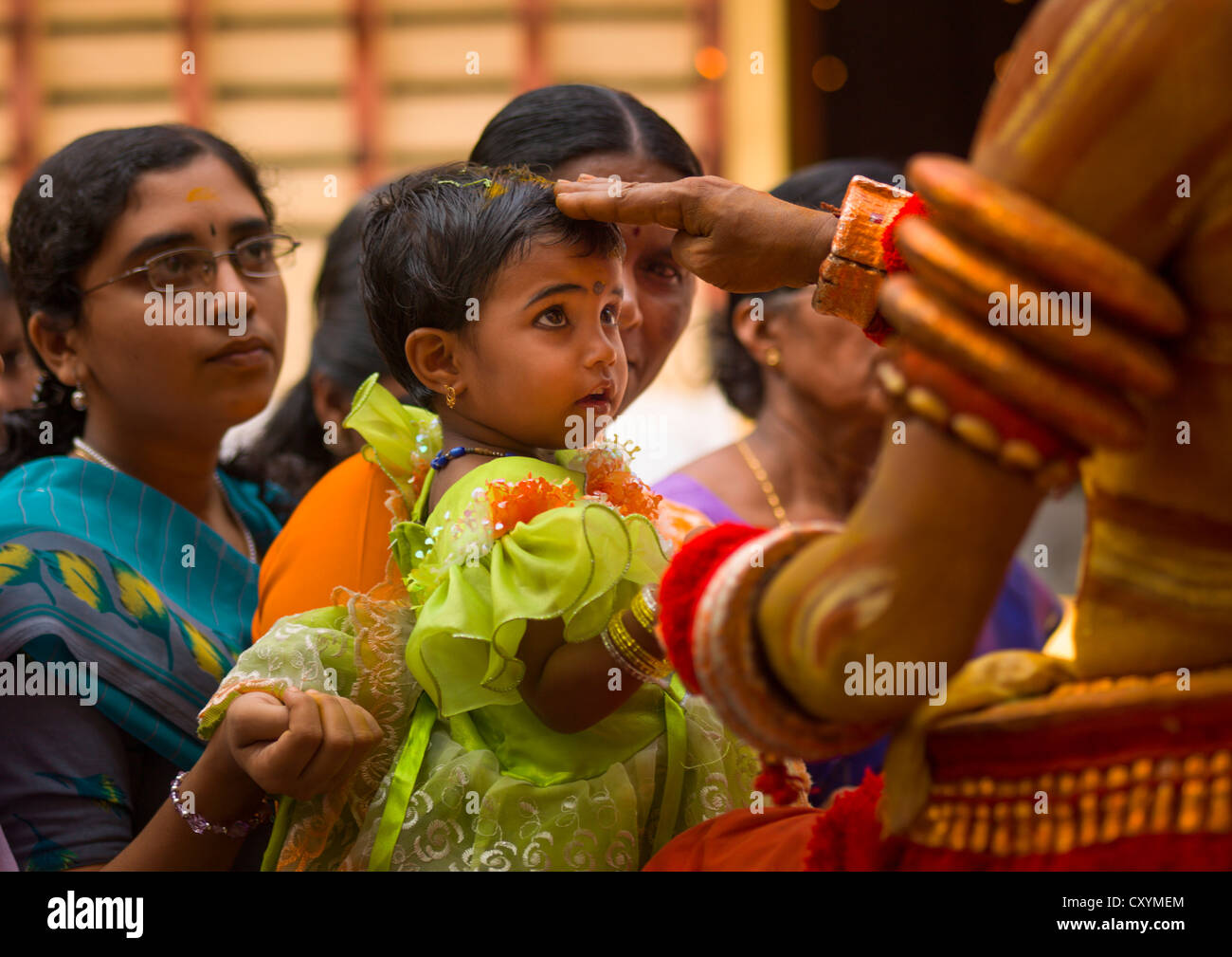 Bambina con pasta di legno di sandalo sul suo i peli nelle braccia di sua madre ha ricevuto la benedizione dal Theyyam, Thalassery, India Foto Stock