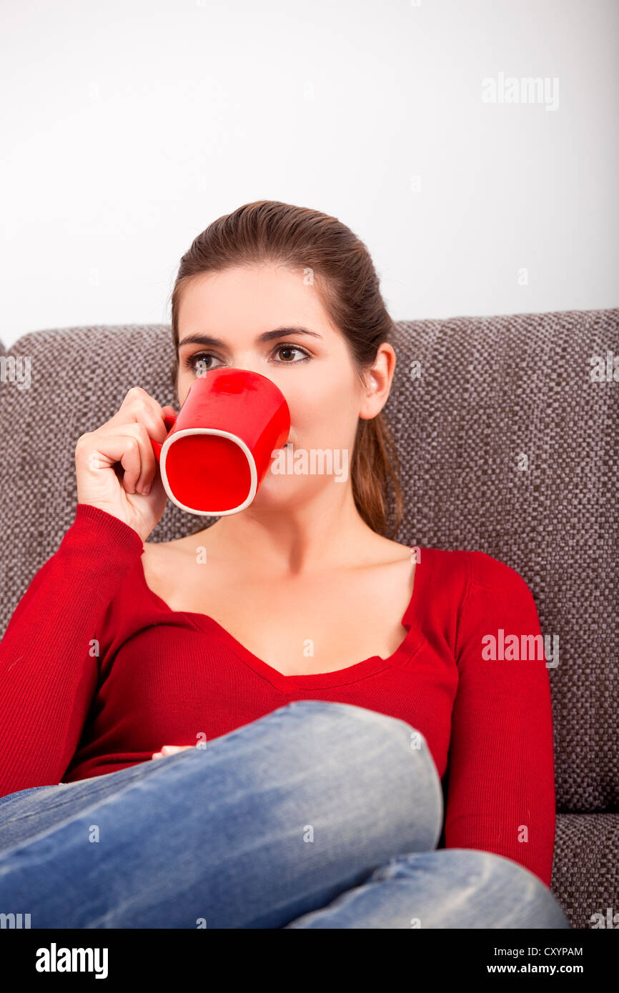Bella donna appoggiata sul divano e di bere il caffè Foto Stock