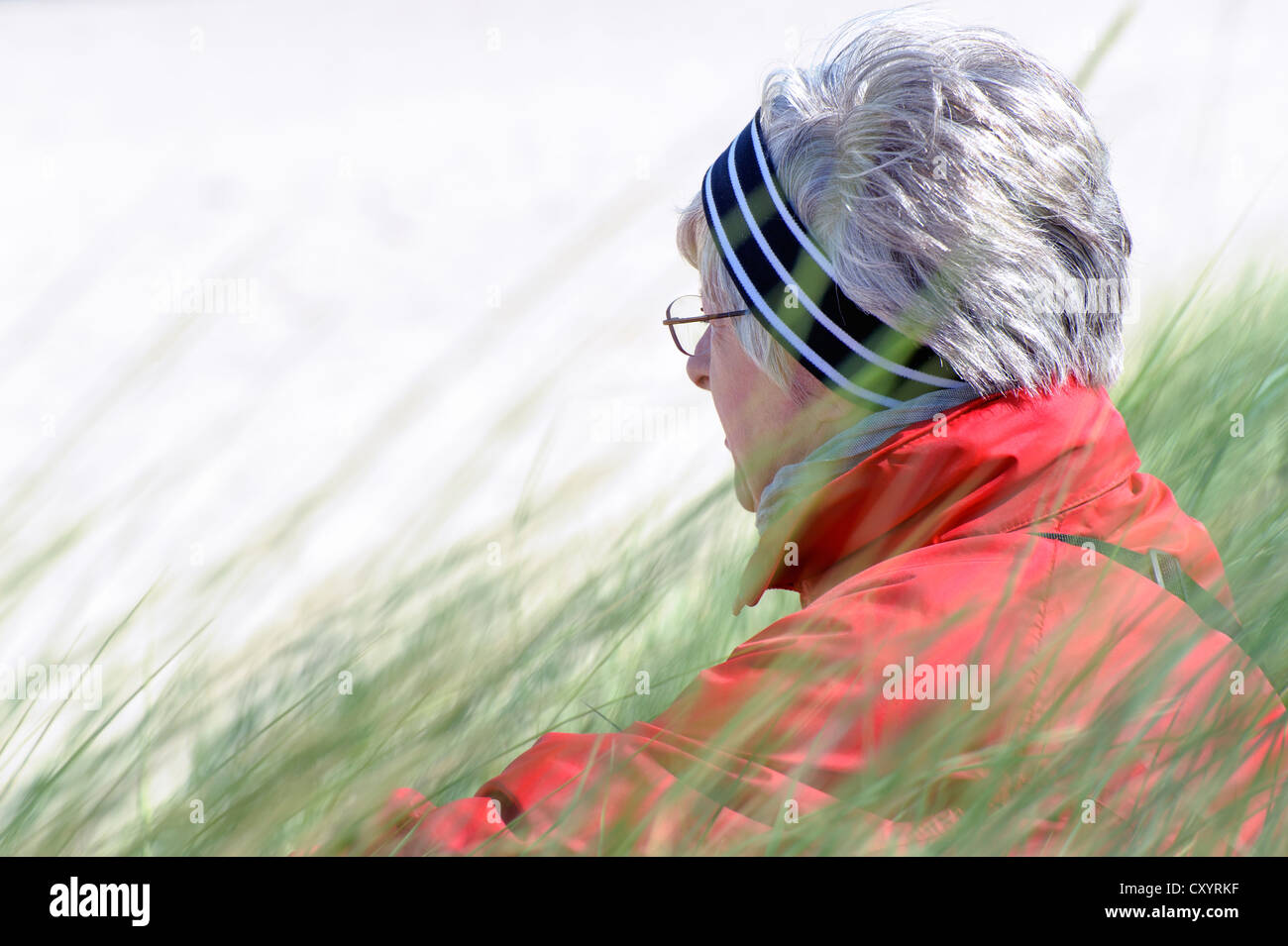 Donna seduta tra l'erba marram sulle dune della Costa Baltica, Meclemburgo-Pomerania Occidentale Foto Stock