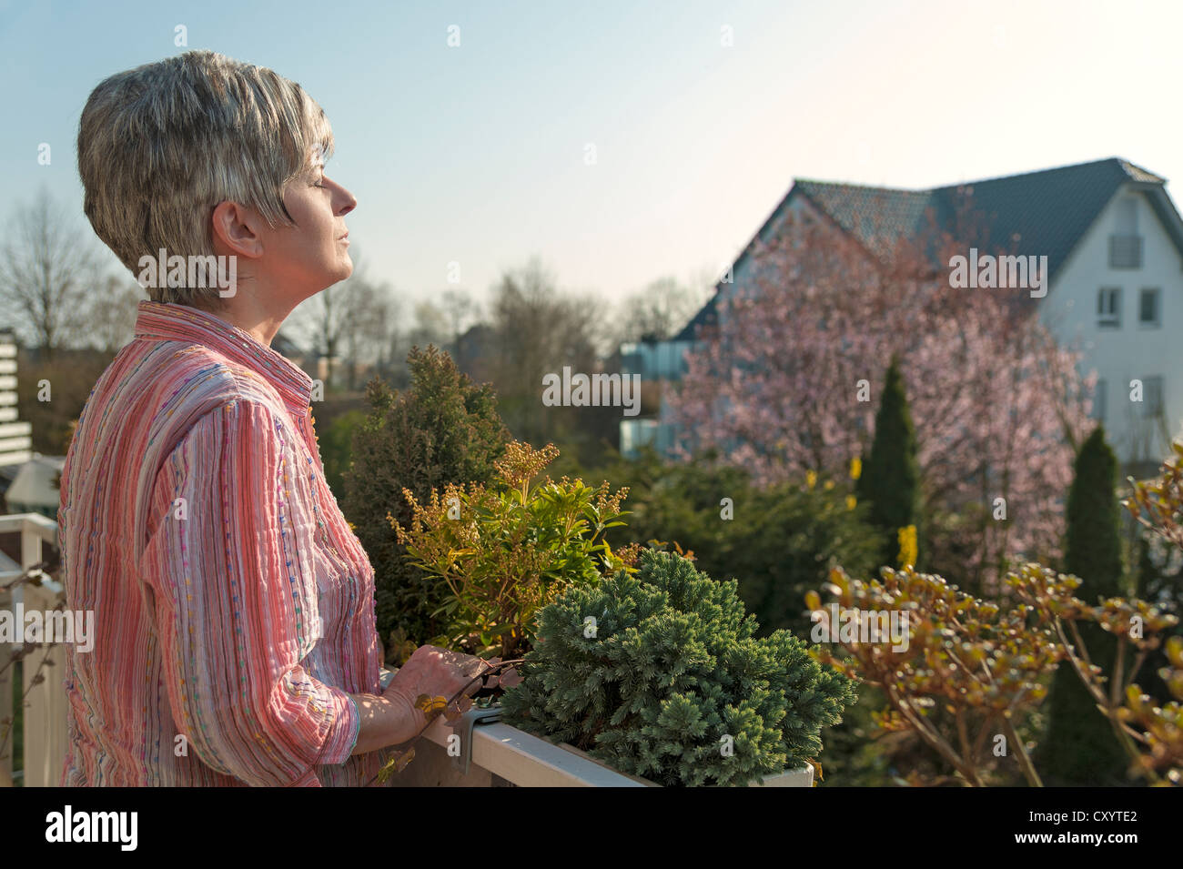 Donna in piedi su un balcone, godersi il sole del mattino, Grevenbroich, Renania settentrionale-Vestfalia Foto Stock