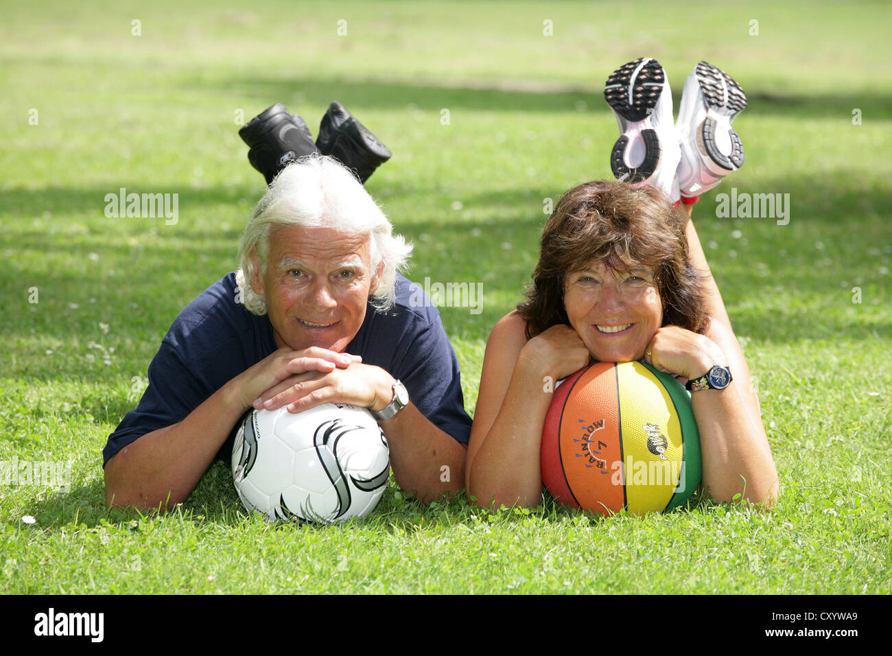 Sorridente coppia senior con due sfere giacente sul prato, Erfurt, Turingia Foto Stock
