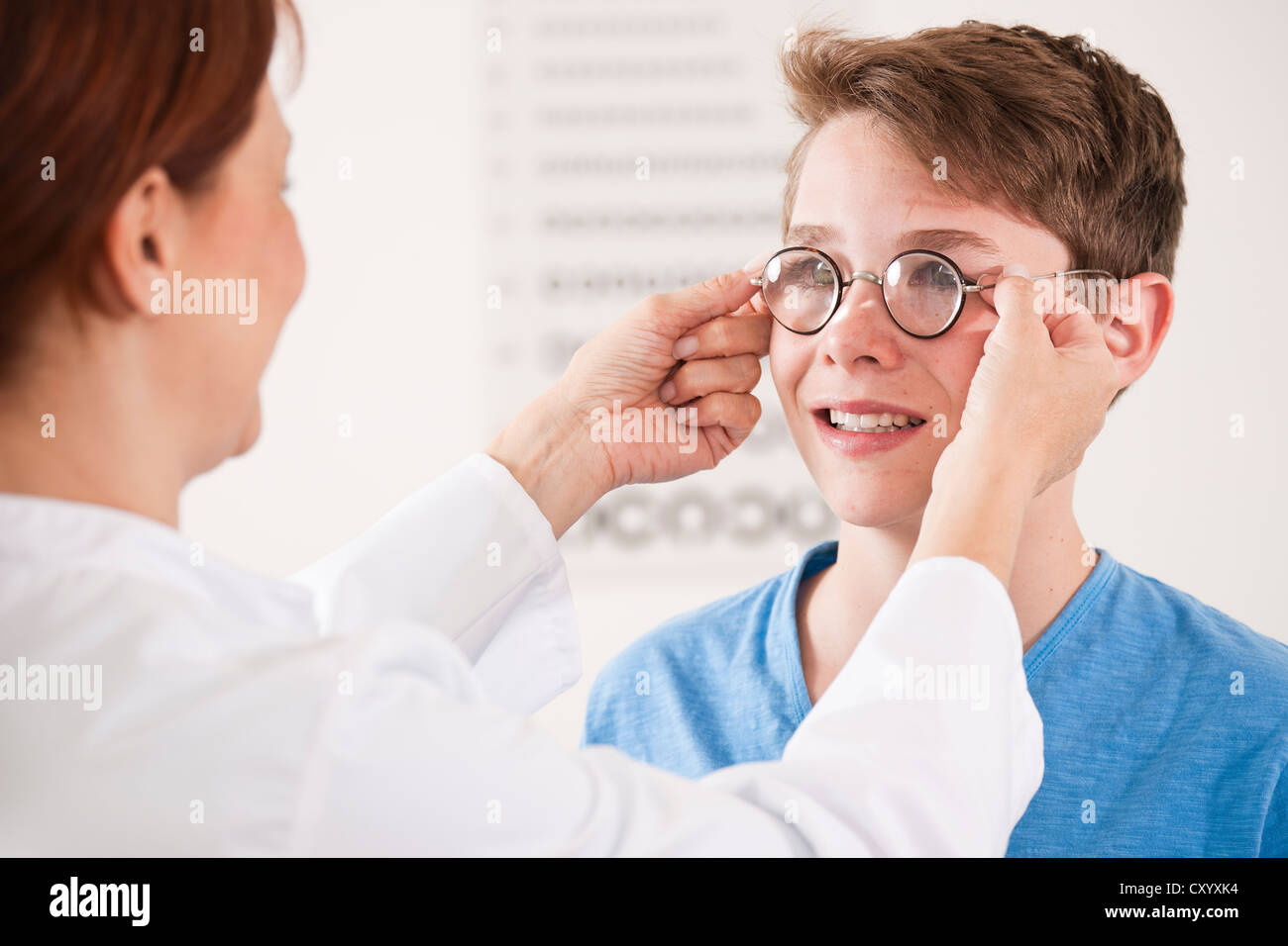 Oculista per mettere un paio di occhiali su un ragazzo adolescente Foto Stock