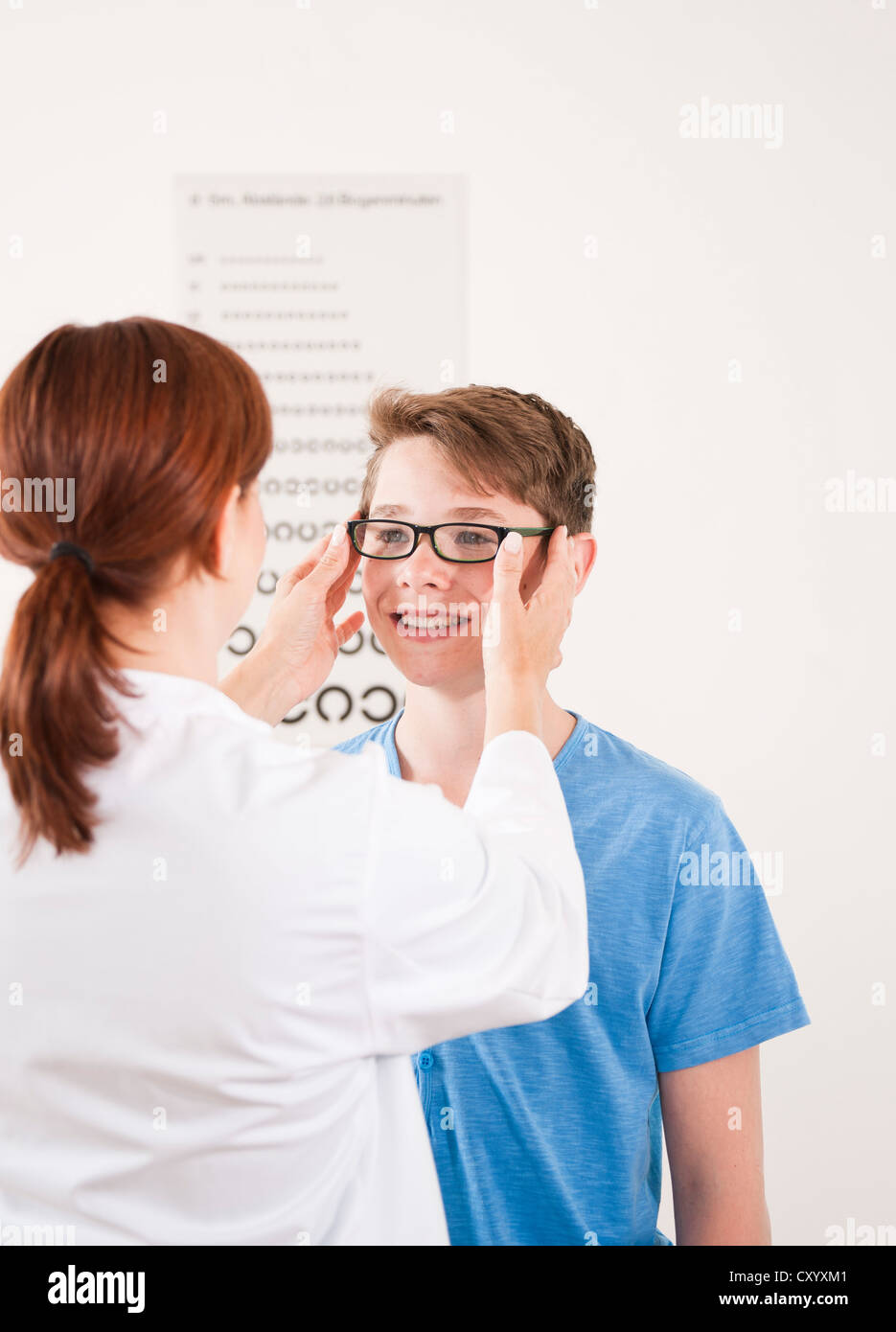 Oculista per mettere un paio di occhiali su un ragazzo adolescente Foto Stock