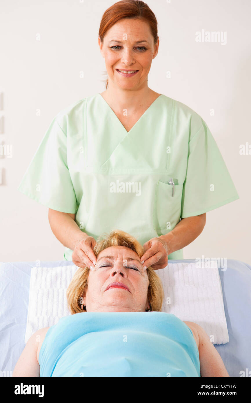 Paziente che viene massaggiato sulla sua templi da un fisioterapista Foto Stock