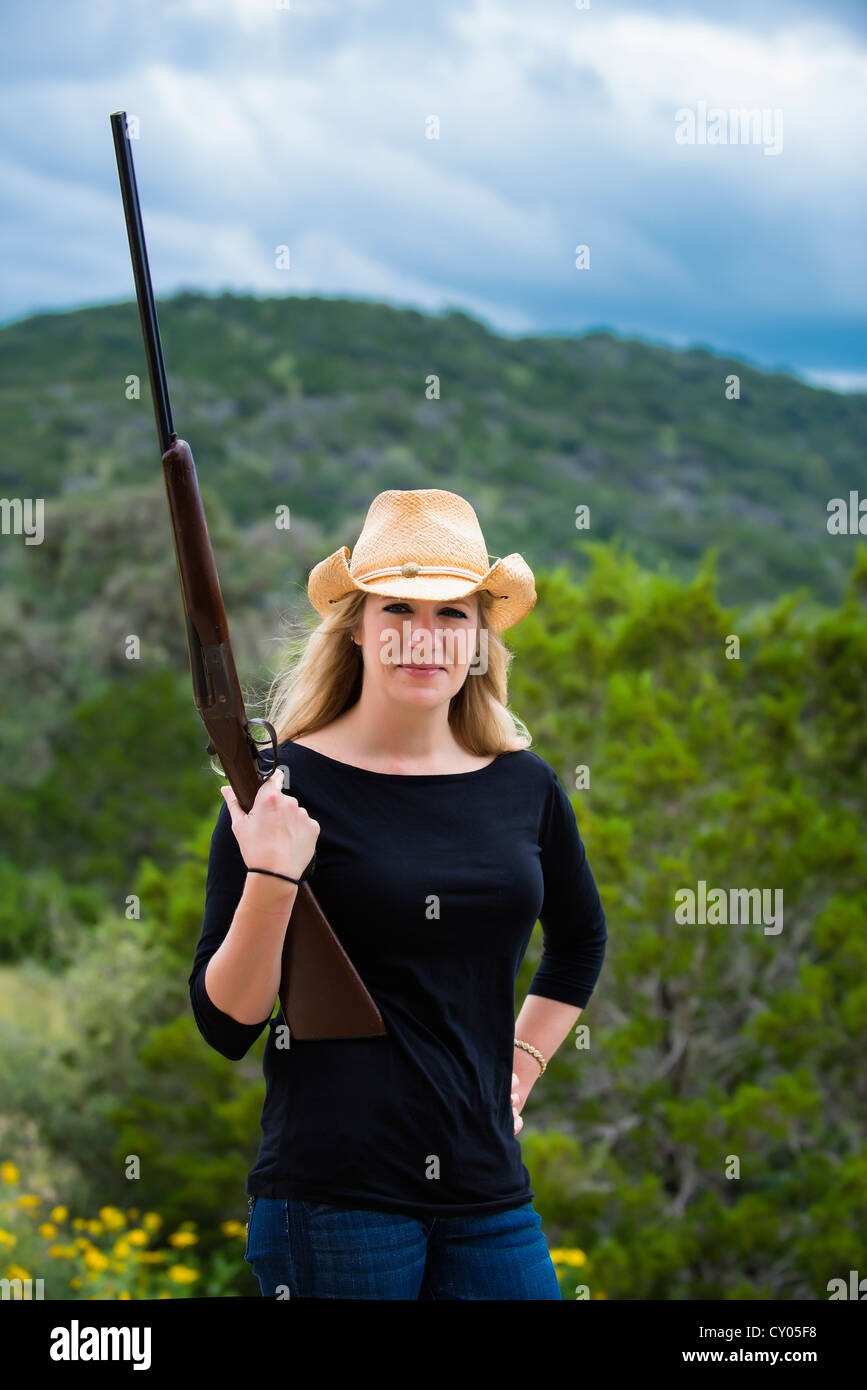 Donna con cappello da cowboy in posa con fucile shotgun Foto Stock