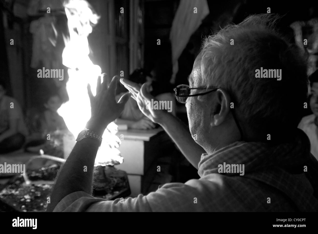 Un indù adoratore passa le sue mani attraverso un rituale sacro fiamma ad Vishram ghat, Mathura, India Foto Stock