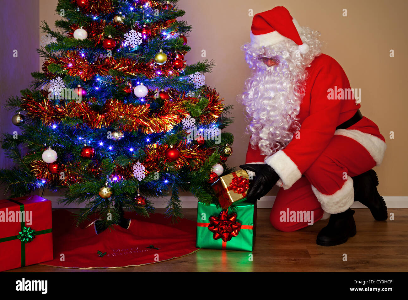 Foto di Babbo Natale Claus erogare presenta e mettere i doni sotto l'albero di Natale. Foto Stock