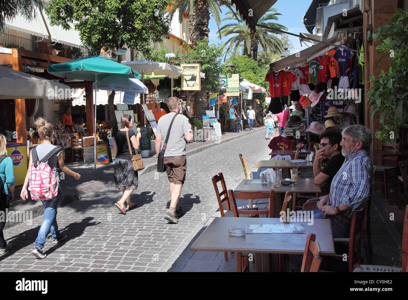 I turisti a piedi passato e seduta a street café città vecchia di Rethymnon, Creta, Grecia Foto Stock