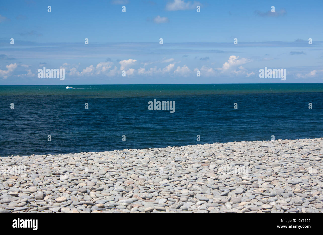 Vuoto spiaggia ghiaiosa che guarda al mare con cielo blu e nuvole cumulus Ceredigion Aberaeron Mid Wales UK Foto Stock