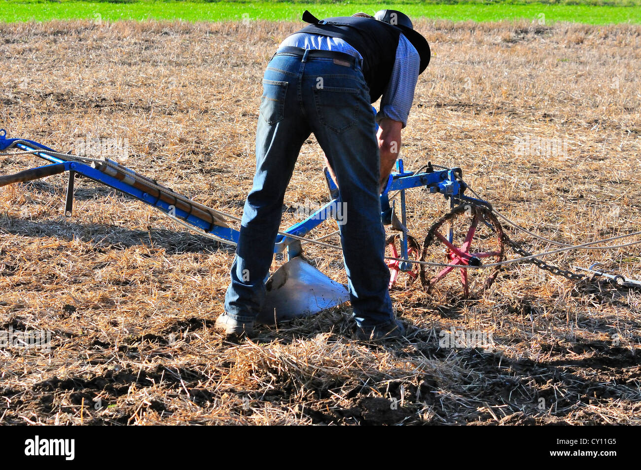 Agricoltore che regola le guide del solco sul suo aratro Howard durante un evento di aratura all'Autumn Countryside Show, West Sussex, Inghilterra, Regno Unito Foto Stock