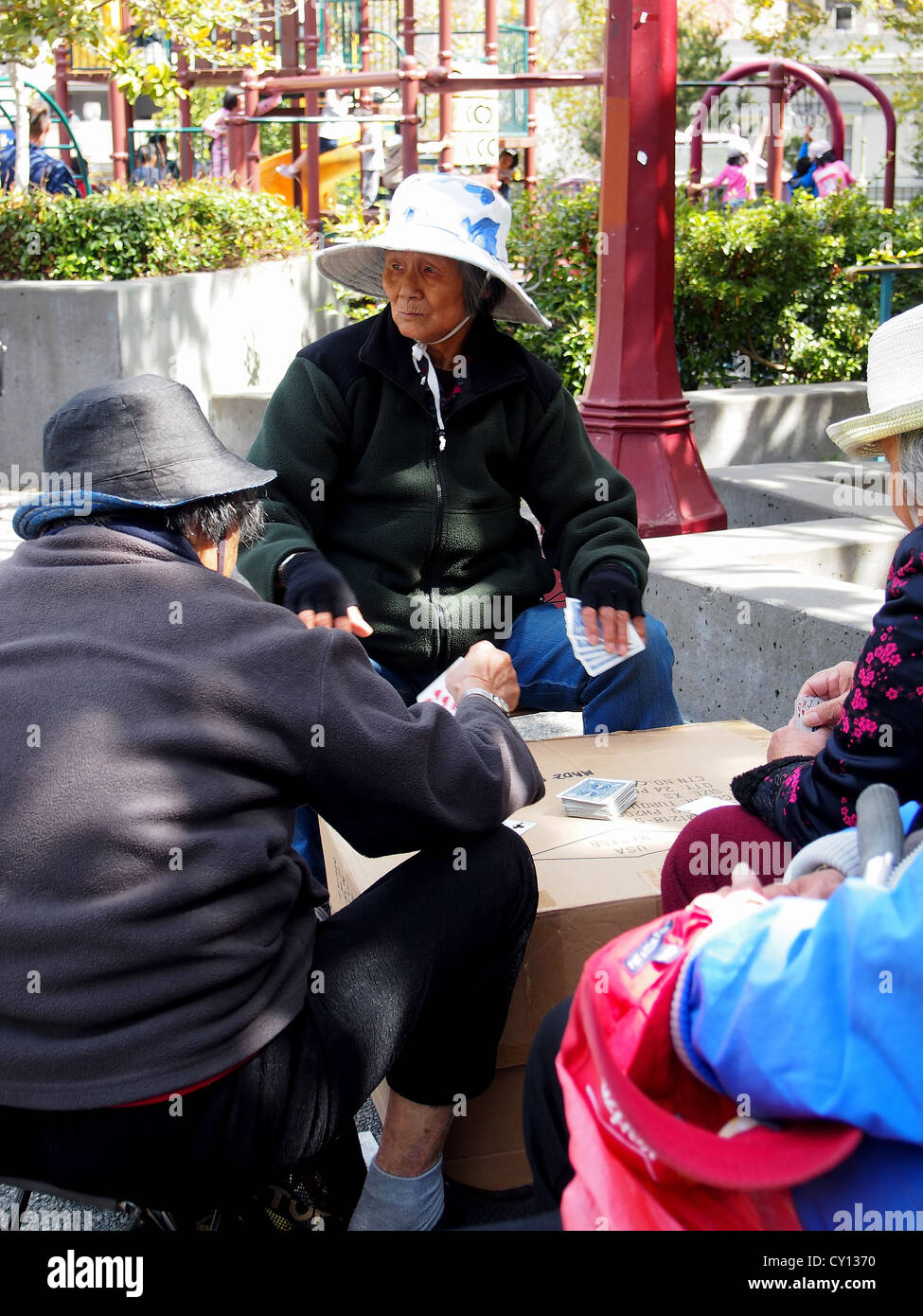 Anziani Le donne cinesi di indossare cappelli e giocare a carte nel parco pubblico, Chinatown di San Francisco Foto Stock