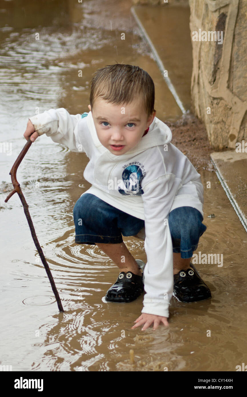 Un ragazzo con autismo esplora l'input sensoriale di un impasto durante un acquazzone. Foto Stock