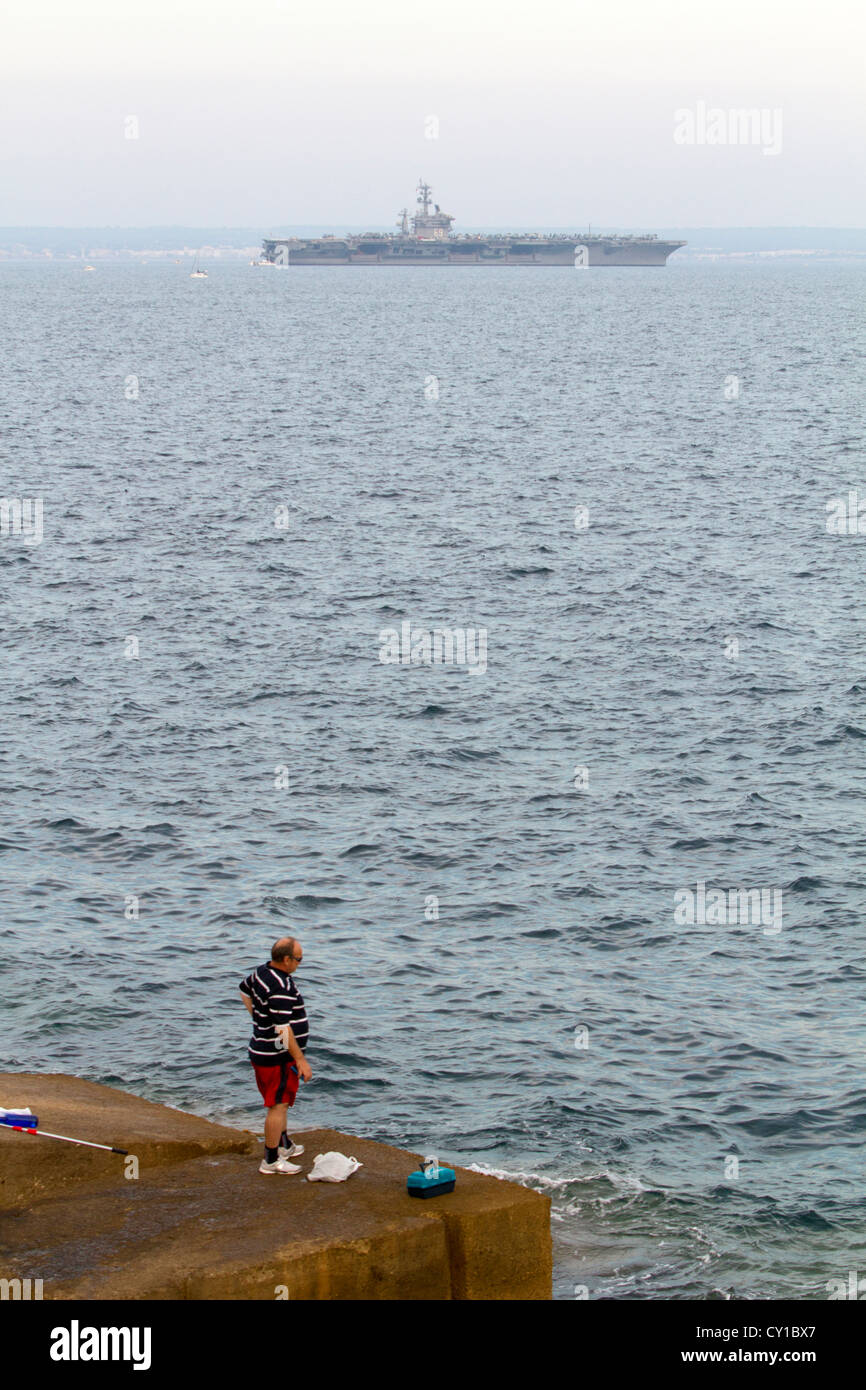 Pescatore e la portaerei USS Dwight D. Eisenhower (CVN-69) sull orizzonte Palma de Maiorca Isole Baleari Spagna Foto Stock