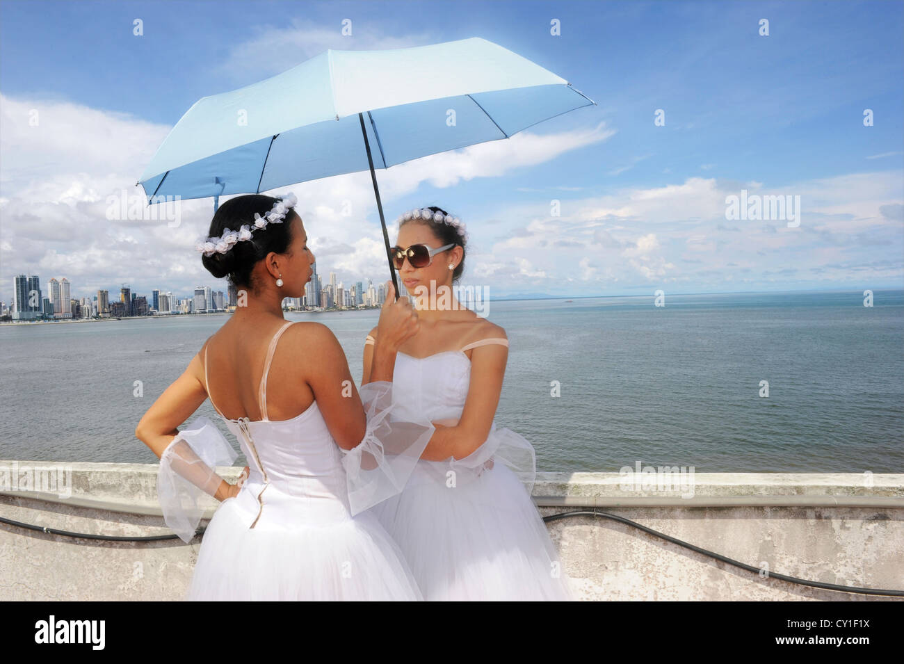 Ballerini di parlare sotto un ombrello blu, con Panamas skyline dietro. Foto Stock