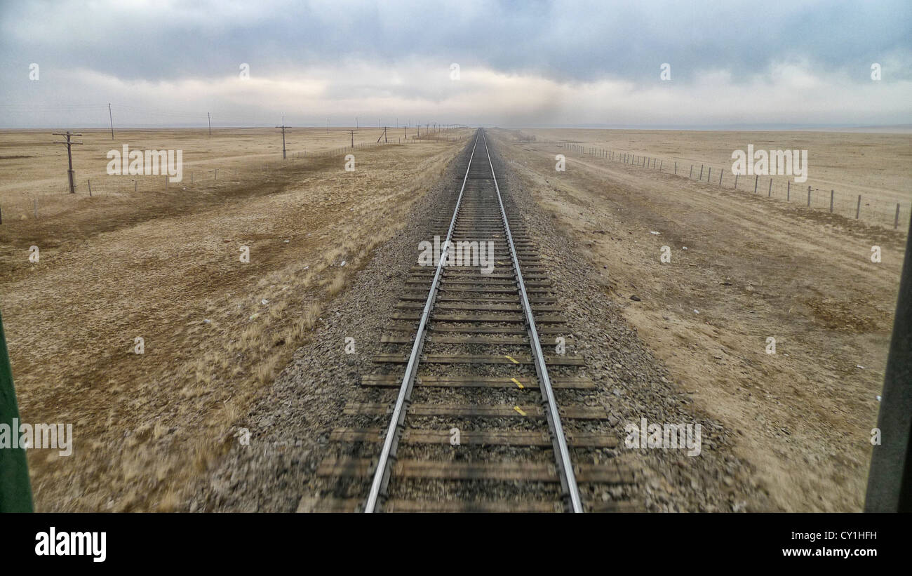 La vista dal retro di un treno che viaggia attraverso il deserto del Gobi tra la Cina e la Mongolia. Foto Stock