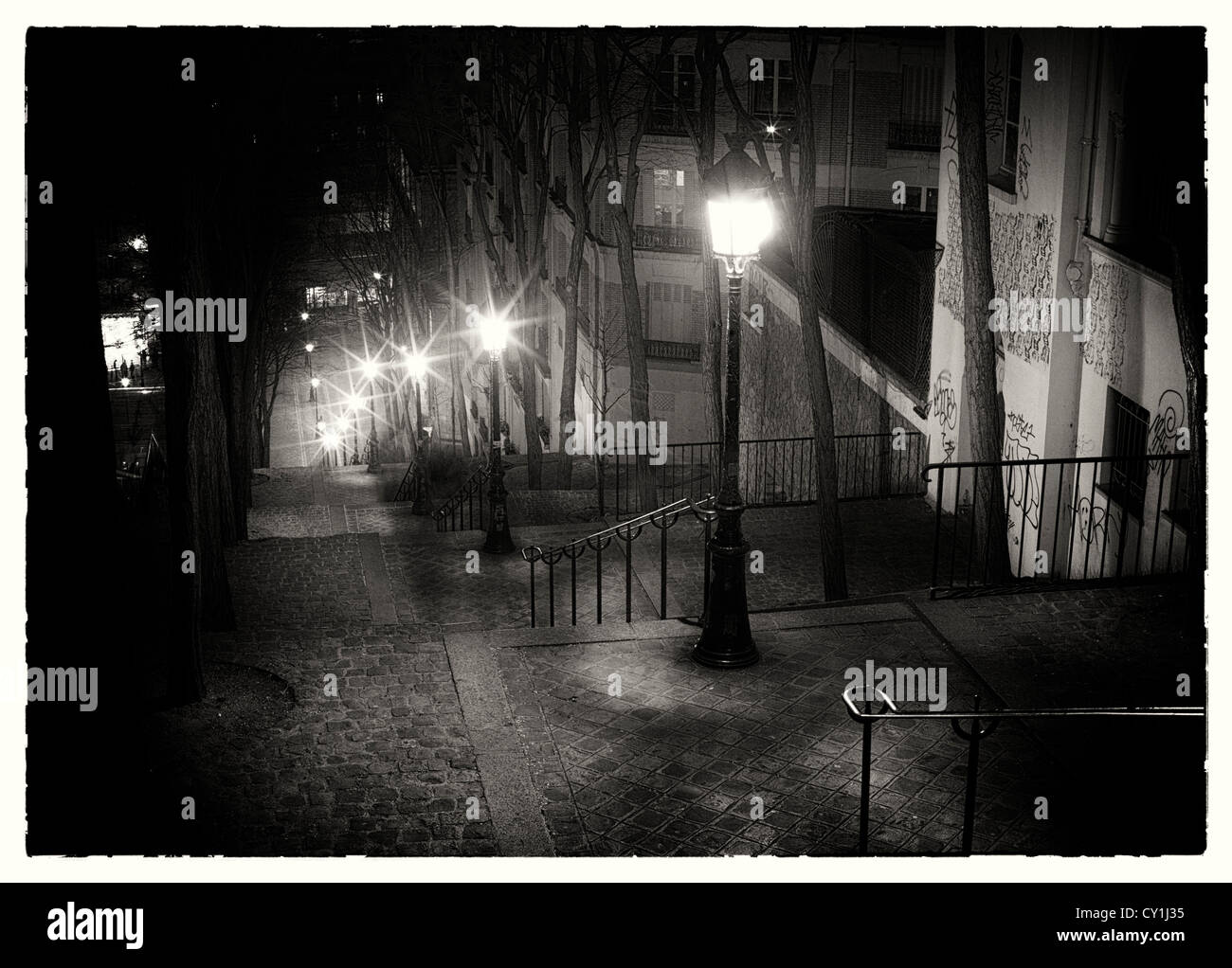 Passi sulla strada parigina di notte con incandescente lampade stradali Foto Stock