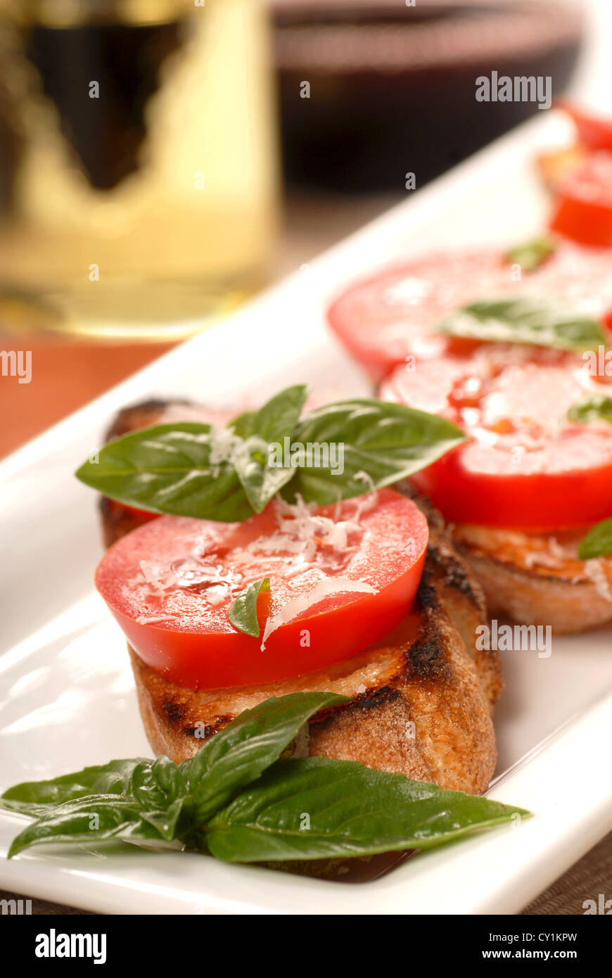 Deliziose bruschette con pomodoro a fette, origano fresco servito su un piatto bianco Foto Stock