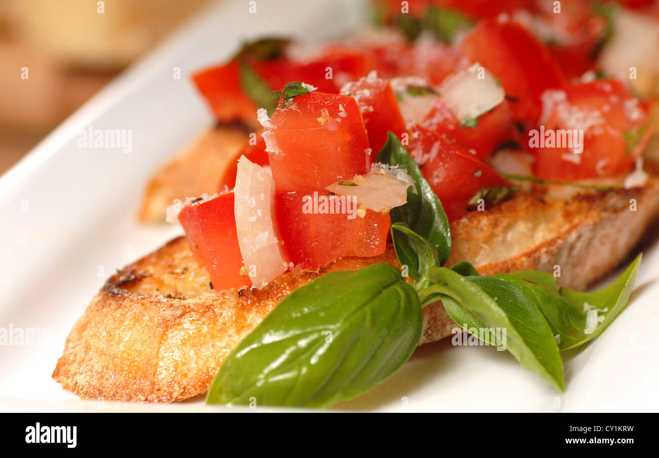 Deliziose bruschette con pomodoro e basilico su un posto bianco Foto Stock