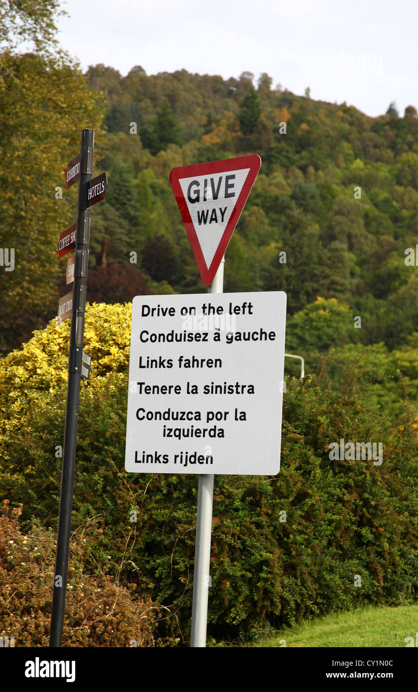 Un segno su un dare modo post raccontando i piloti alla guida a sinistra in diverse lingue per i turisti stranieri in Scozia Foto Stock