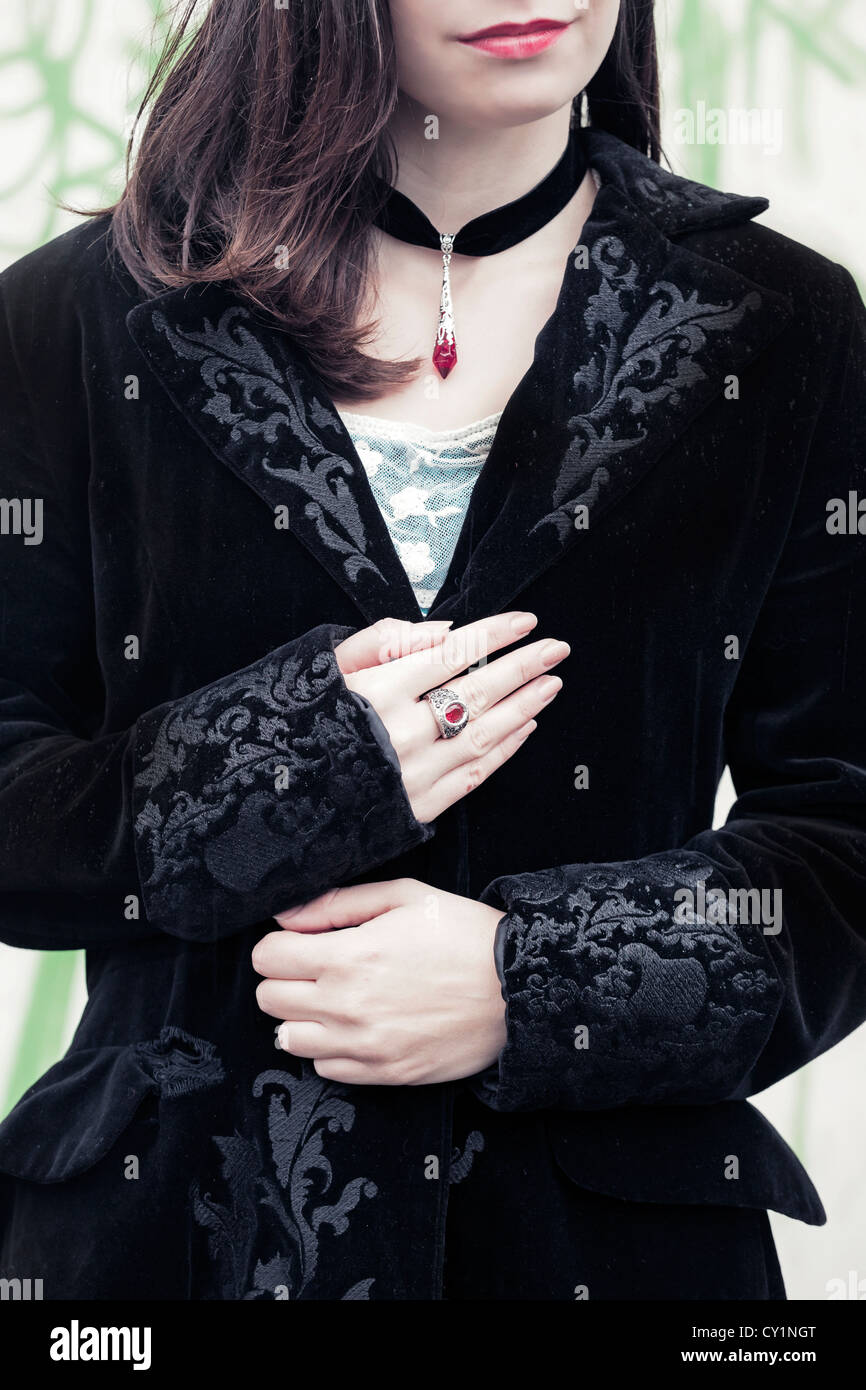 Una donna in un mantello nero con un anello rosso Foto Stock