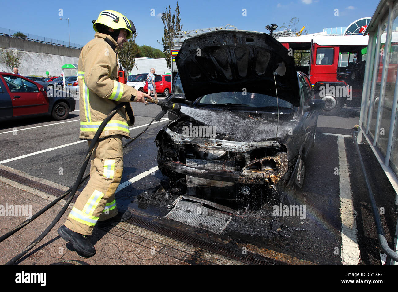 Un vigile del fuoco nella foto messa fuori un auto che ha preso fuoco nel calore in ASDA car park in Brighton, East Sussex, Regno Unito. Foto Stock