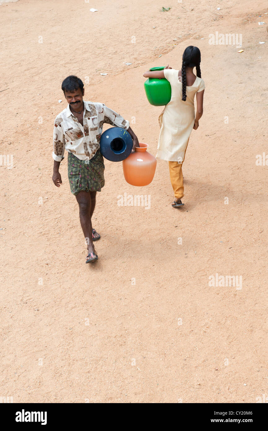 Rurale villaggio indiano l uomo e la ragazza adolescente per la raccolta delle acque da un comune serbatoio di acqua. Andhra Pradesh, India Foto Stock