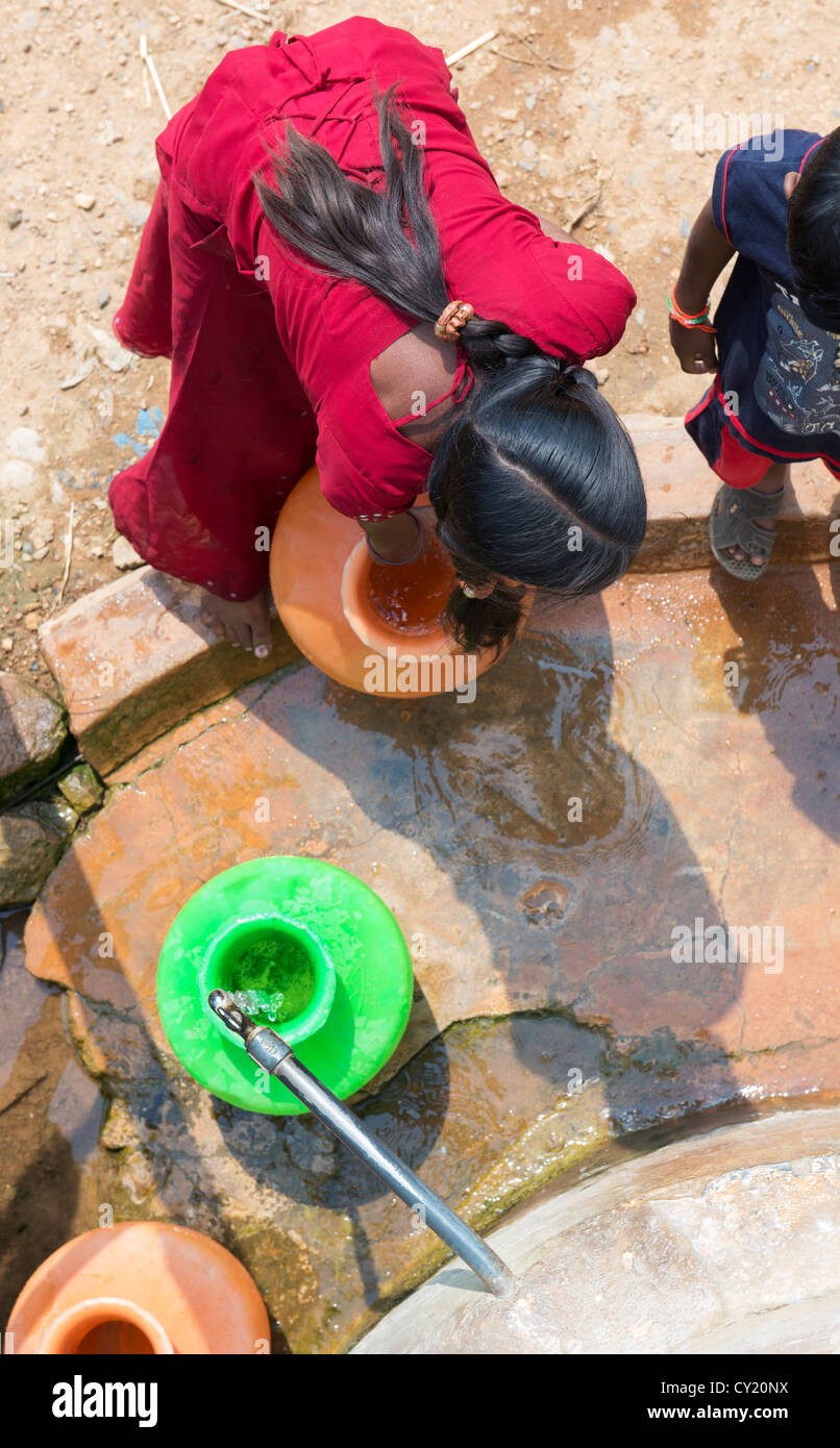 Rurale villaggio indiano ragazza raccolta di acqua da un comune serbatoio di acqua. Andhra Pradesh, India Foto Stock