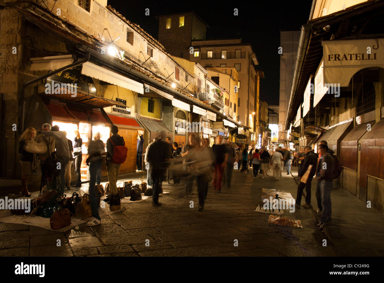 I turisti camminando sul Ponte Vecchio lungo i negozi nel centro storico di Firenze di notte, Toscana, Italia Foto Stock