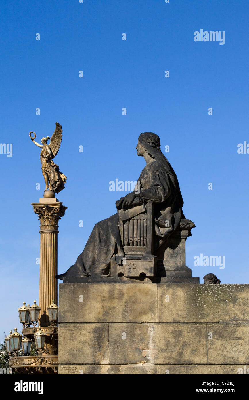 Statua di pietra a Praga la Vergine Maria con un Angelo dorato in background con un blu sly Foto Stock