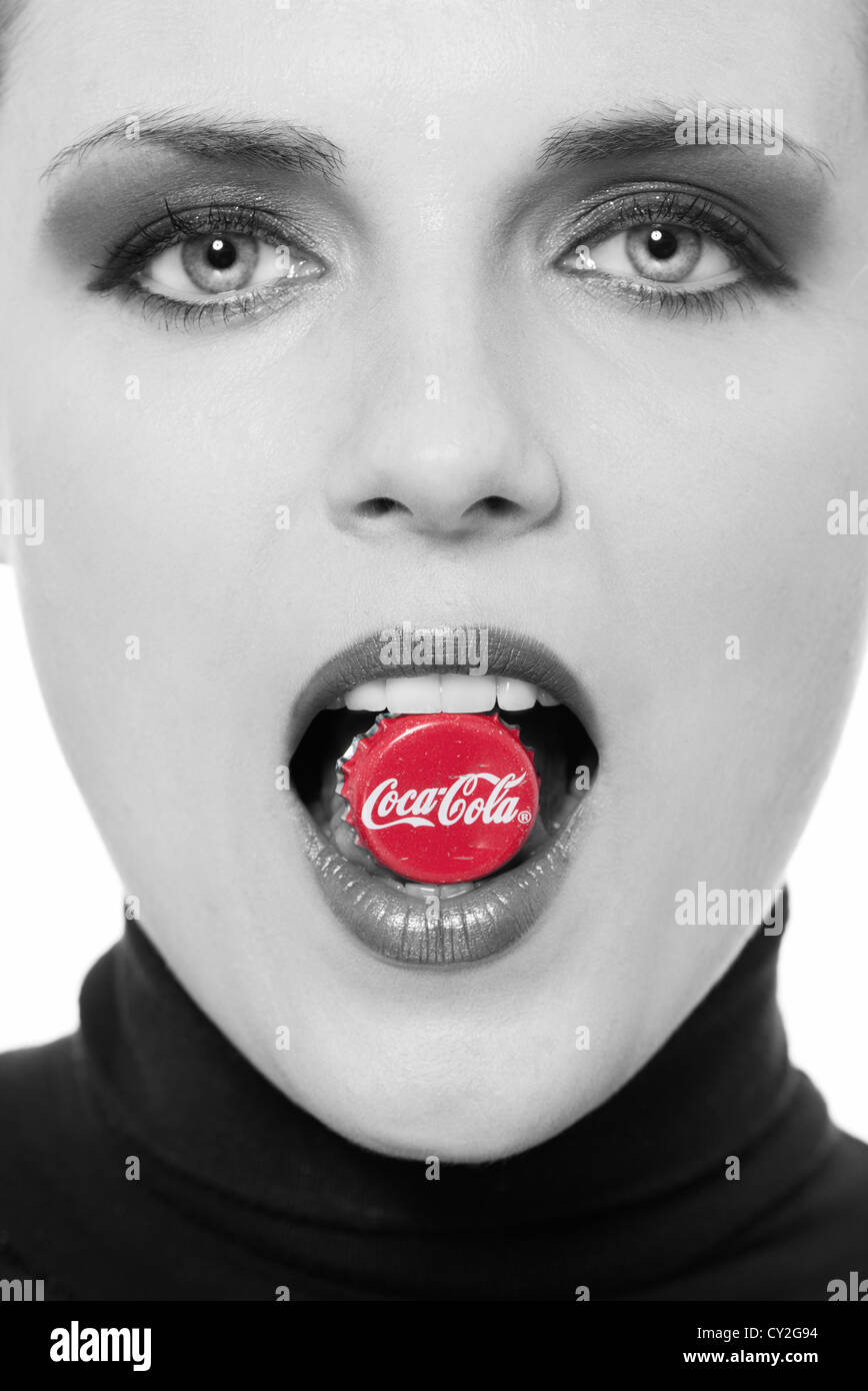 Donna con una coca cola tappo di bottiglia top tra i suoi denti Foto Stock