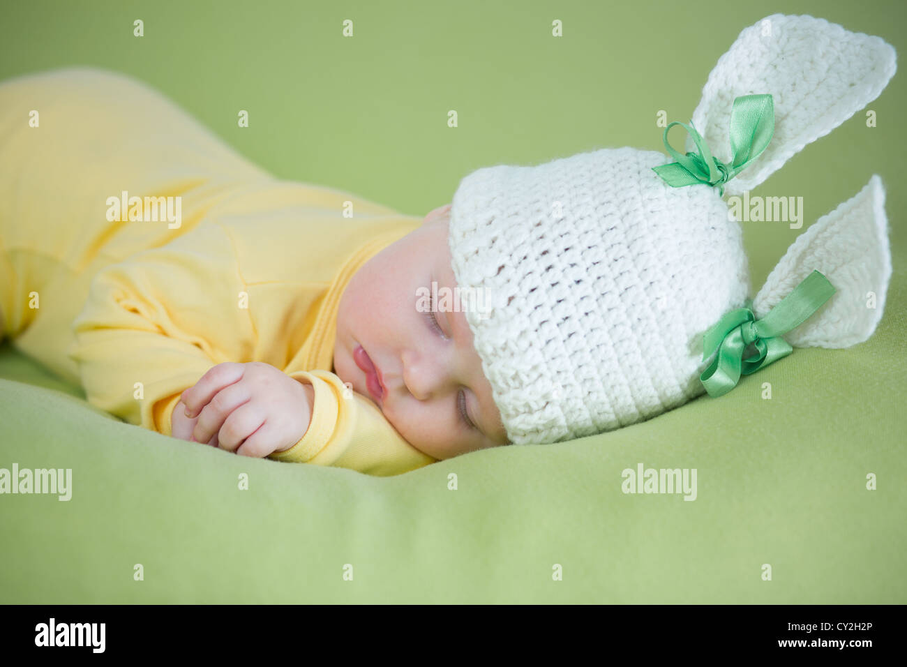 Sleeping bunny baby in funny hat su sfondo verde Foto Stock